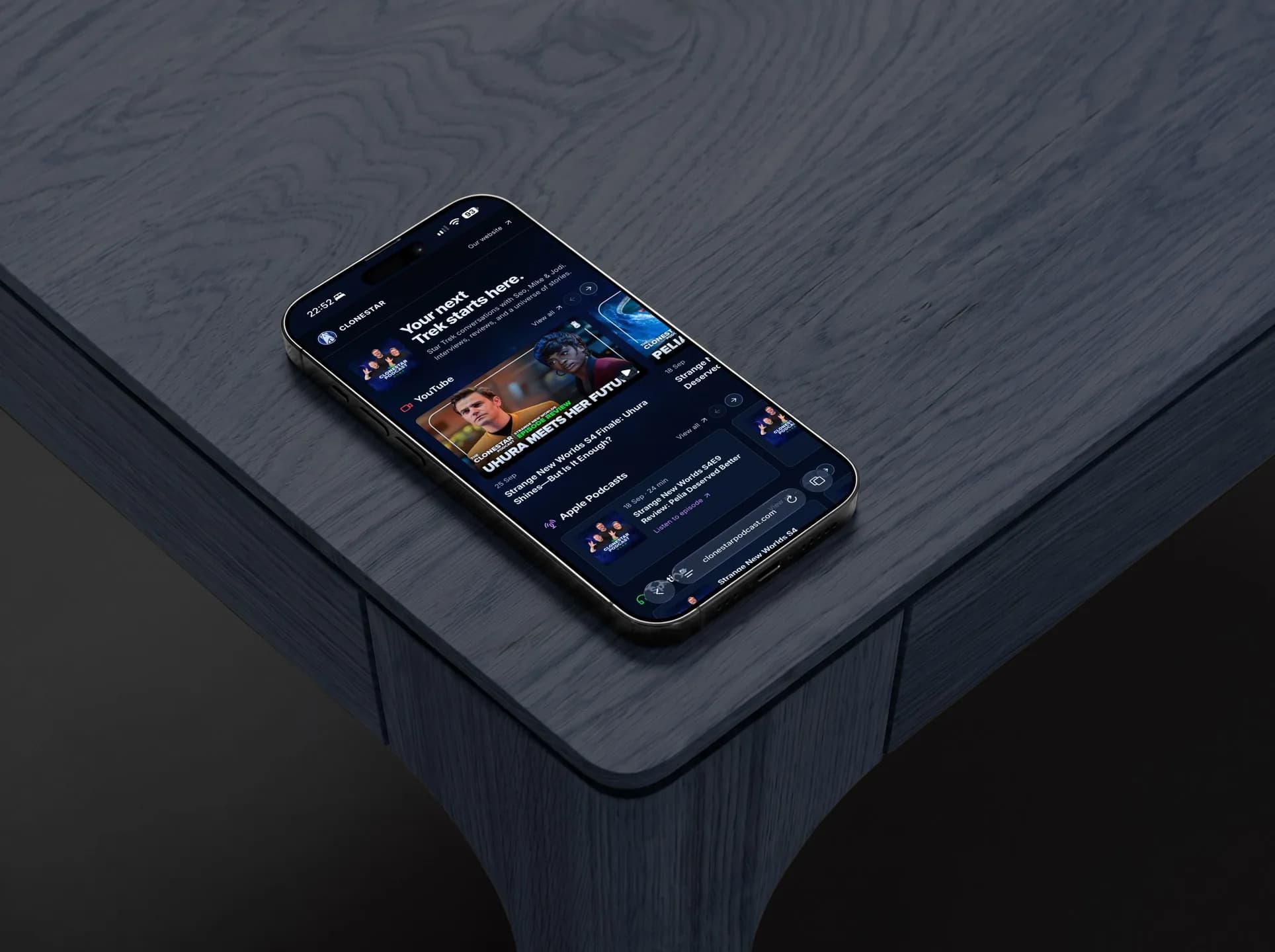 The Clonestar Podcast website on an iPhone lying on a dark wooden table