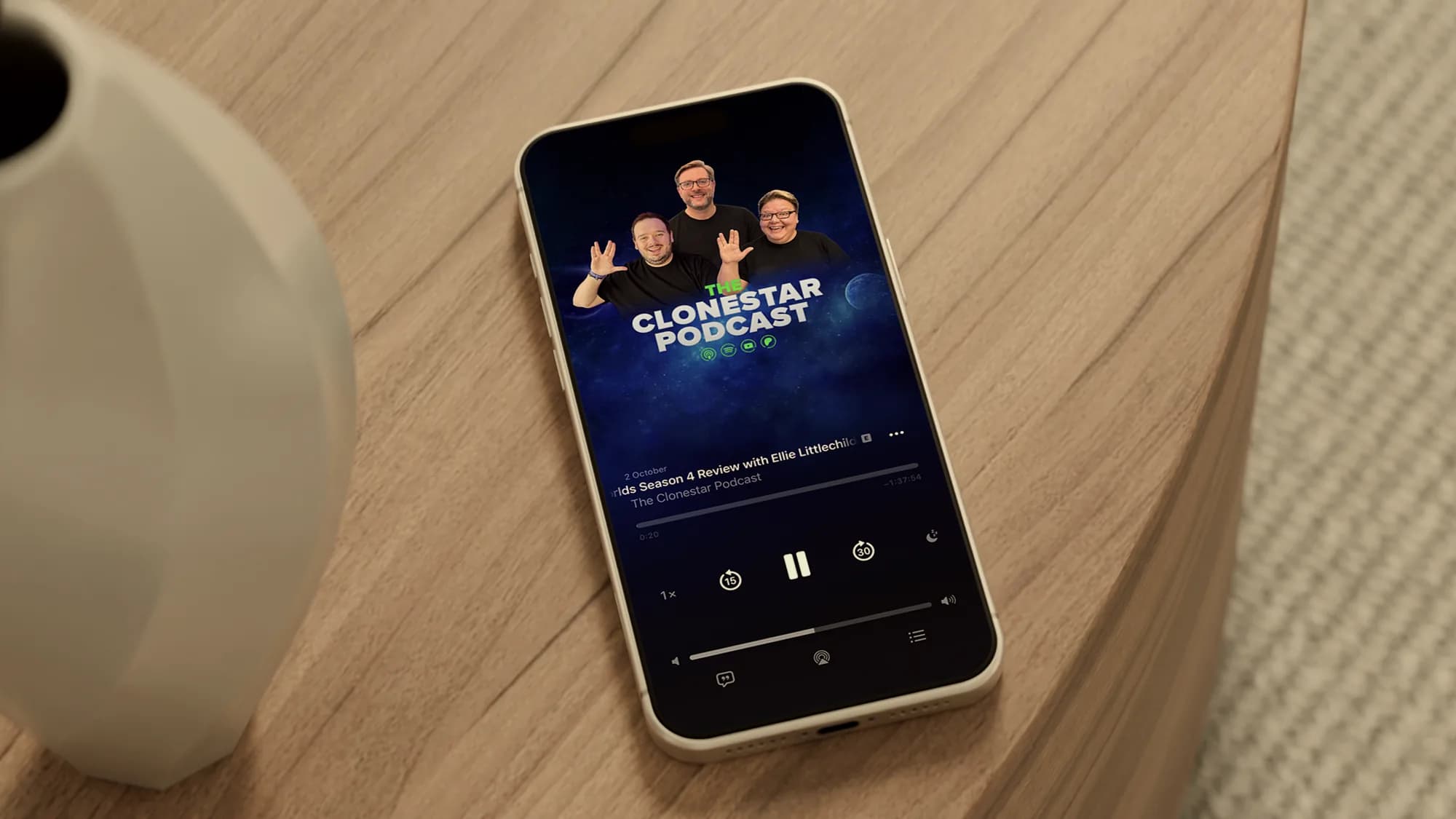 The Clonestar Podcast playing in Apple Podcasts on an iPhone, lying on an oak side table