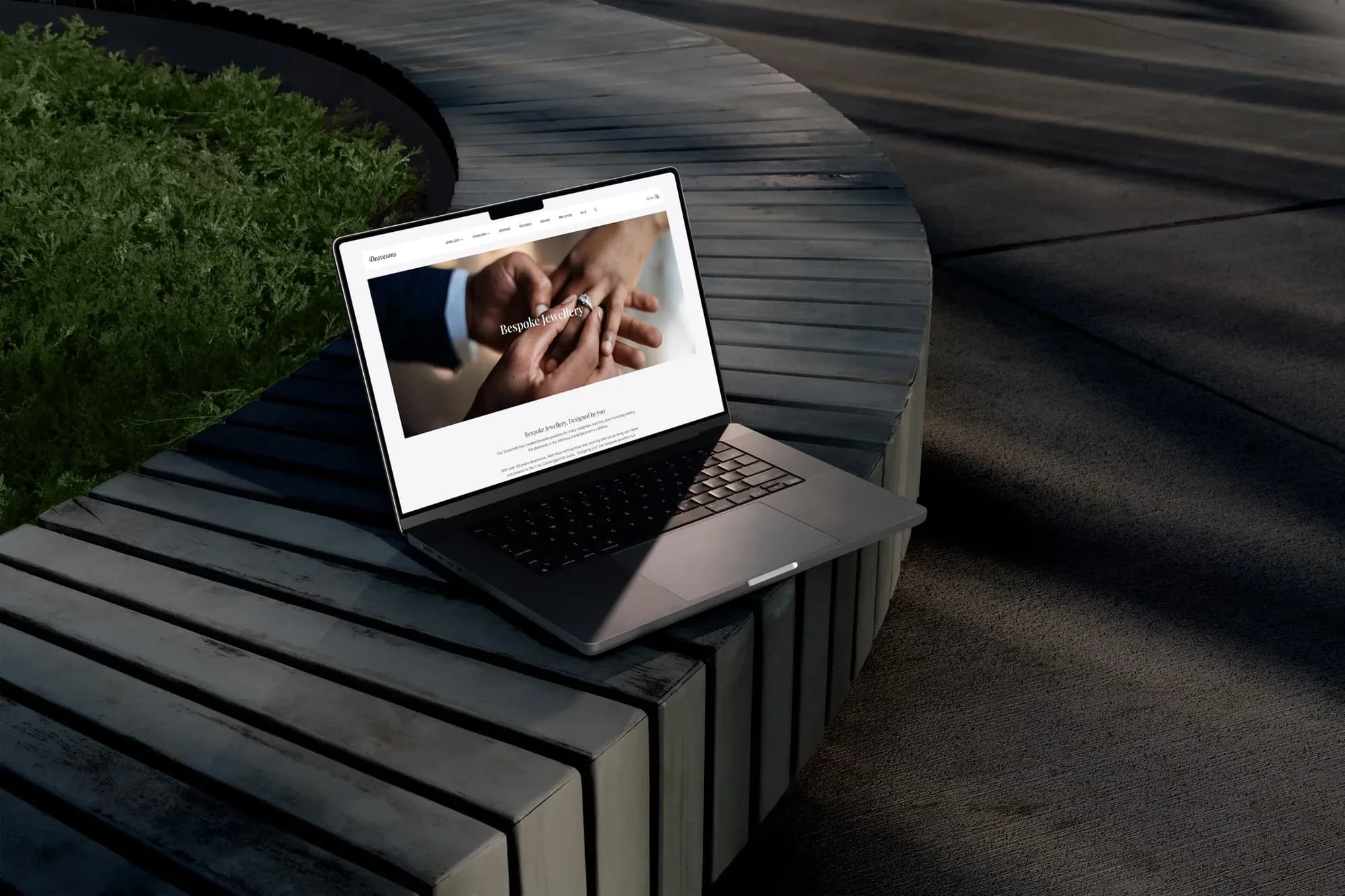 The Deavesons bespoke jewellery page open on a laptop resting on a curved wooden bench