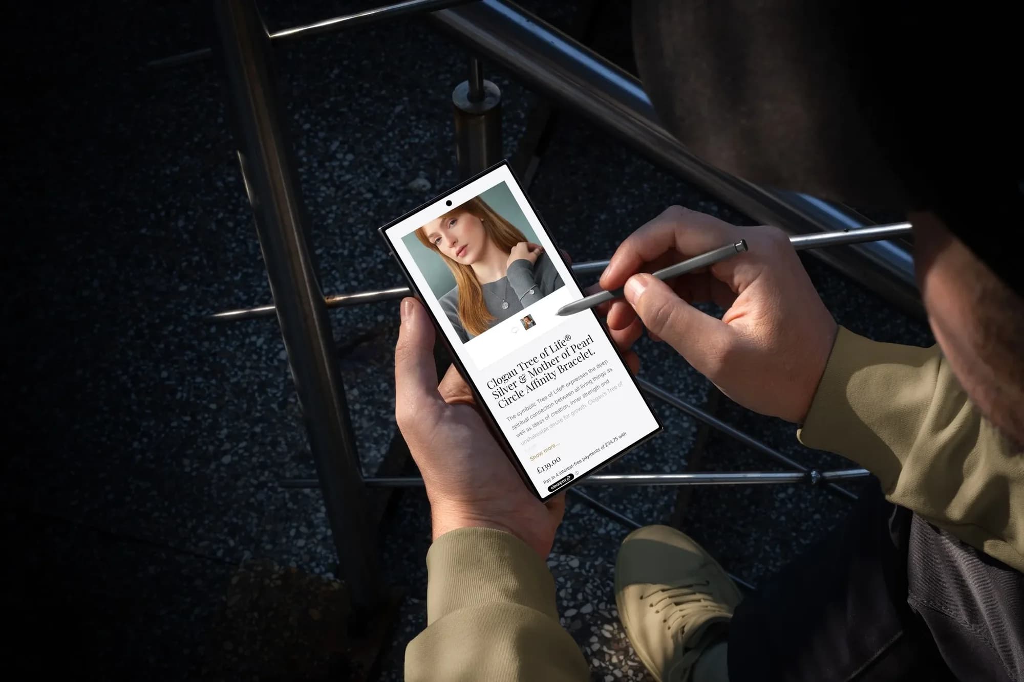 A Deavesons product page for a Clogau Tree of Life bracelet on a smartphone, held with a stylus