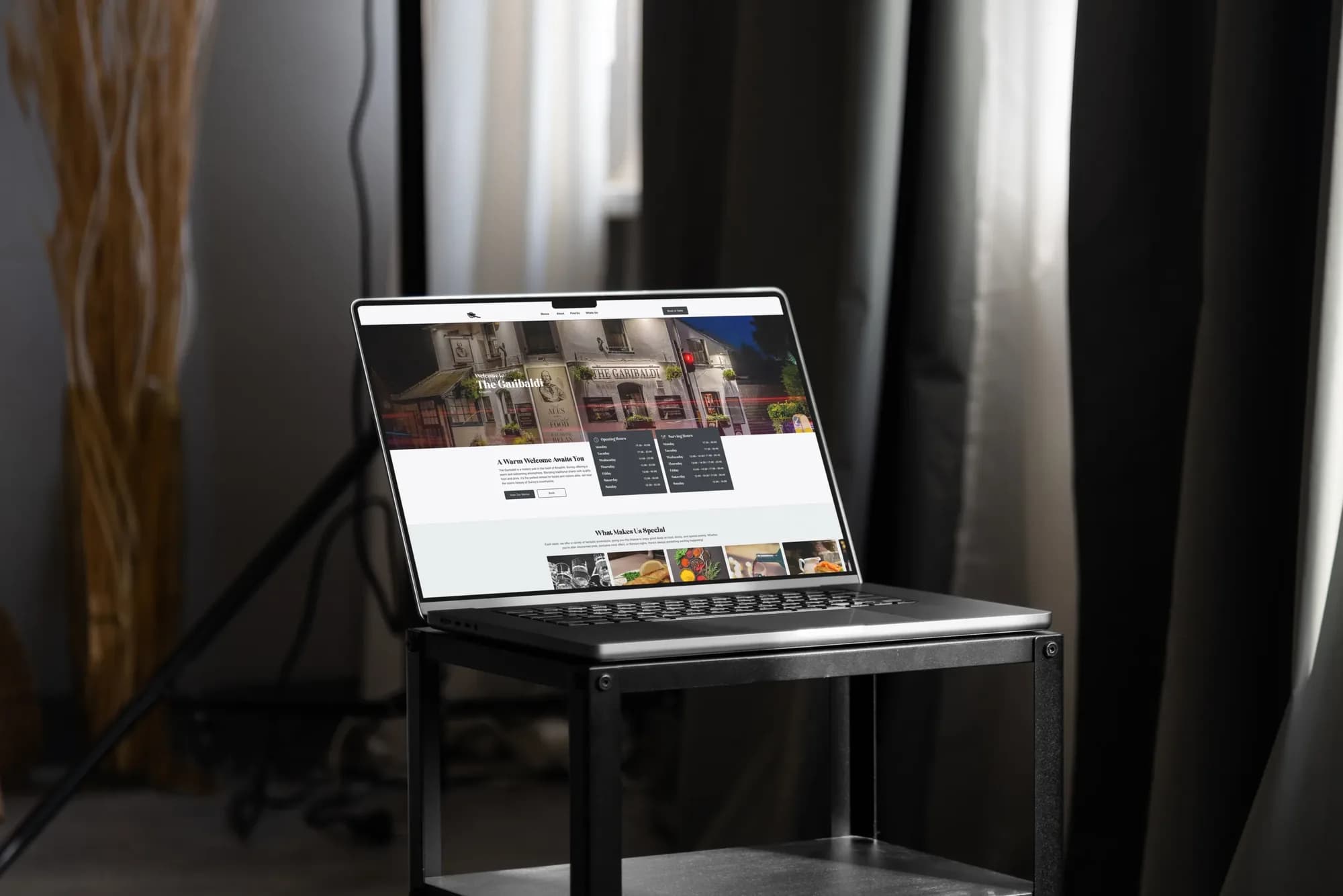 The Garibaldi homepage on a laptop: the pub at night, with opening and serving hours below