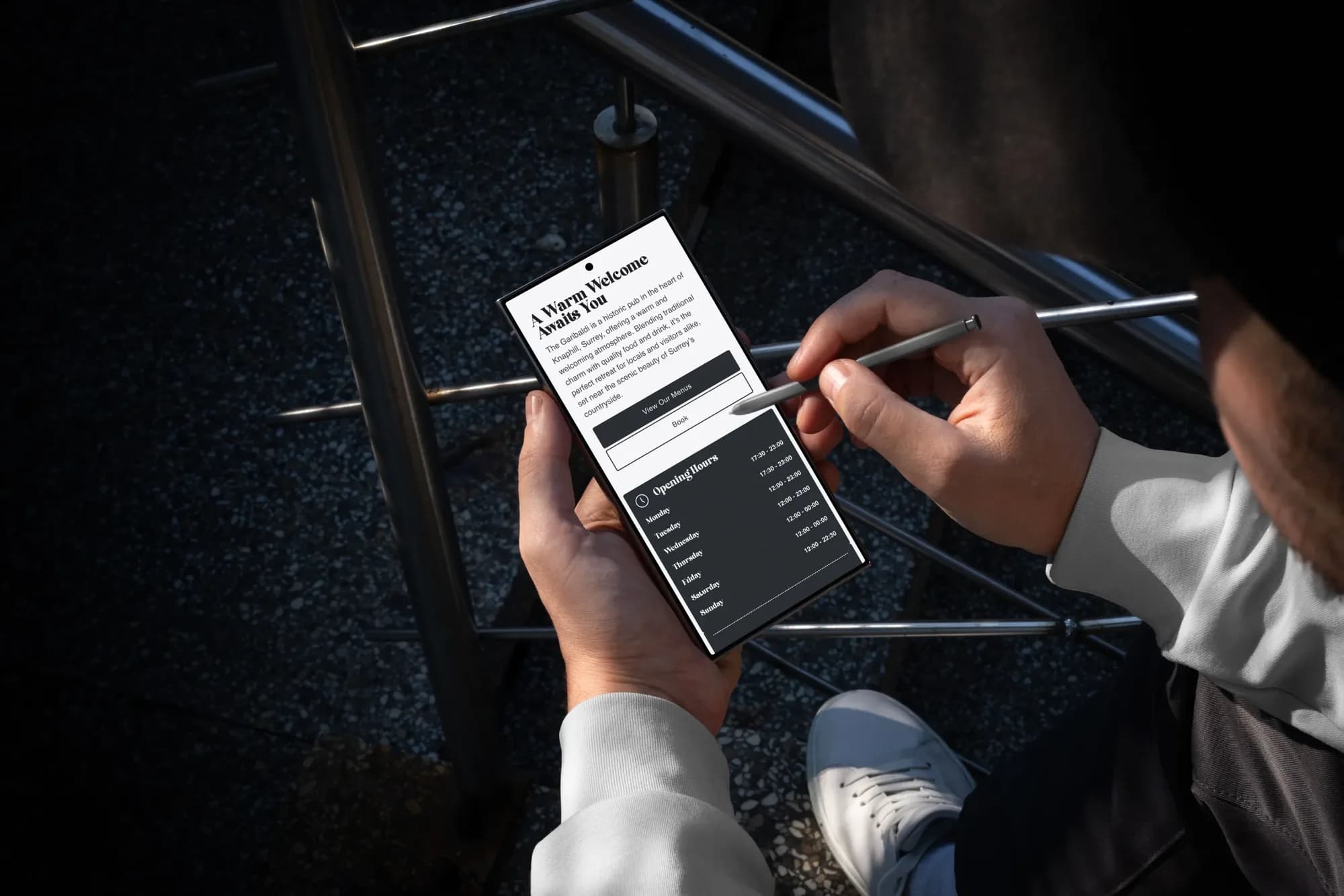 The Garibaldi website on a phone, held in two hands with a stylus