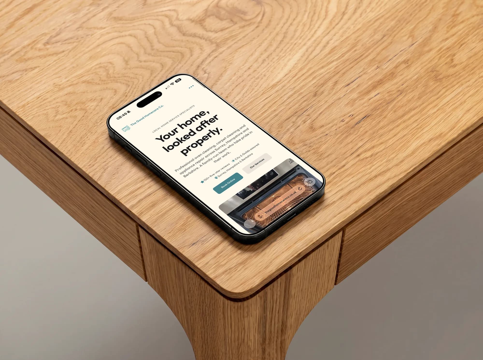The Good Homecare Co. homepage on an iPhone, lying on an oak table