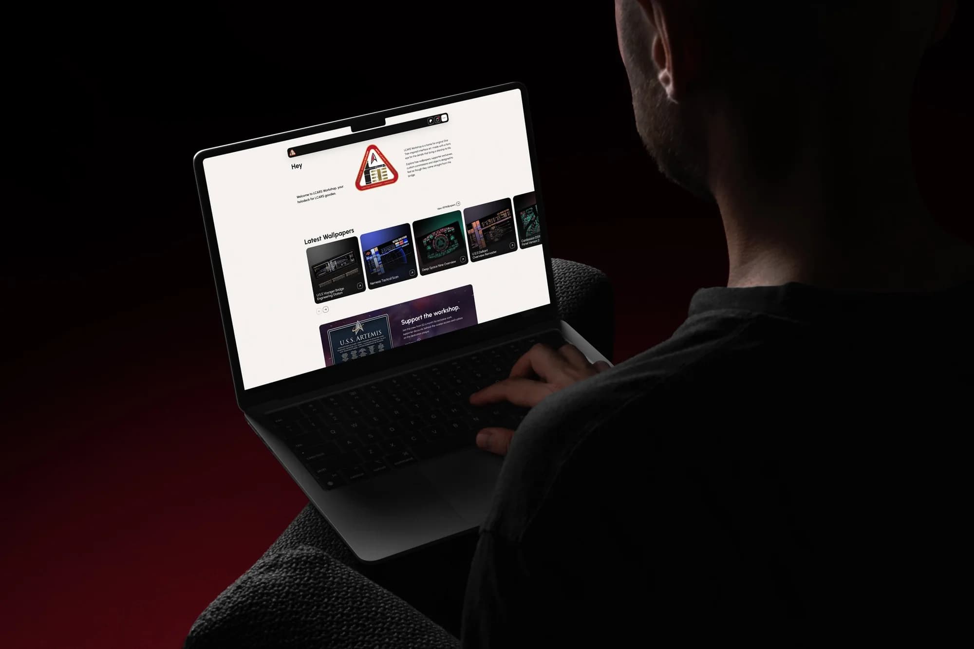 The LCARS Workshop website open on a MacBook, seen over someone’s shoulder in a dark red room