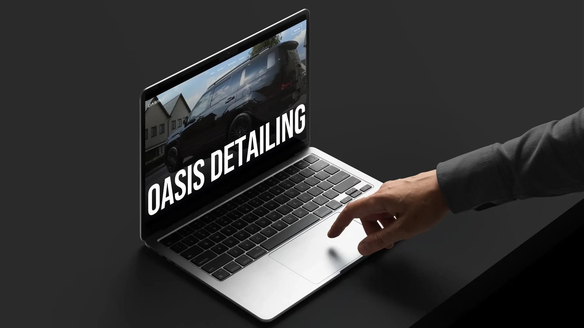 The Oasis Detailing website on a MacBook, with a black SUV and the words Oasis Detailing across the screen