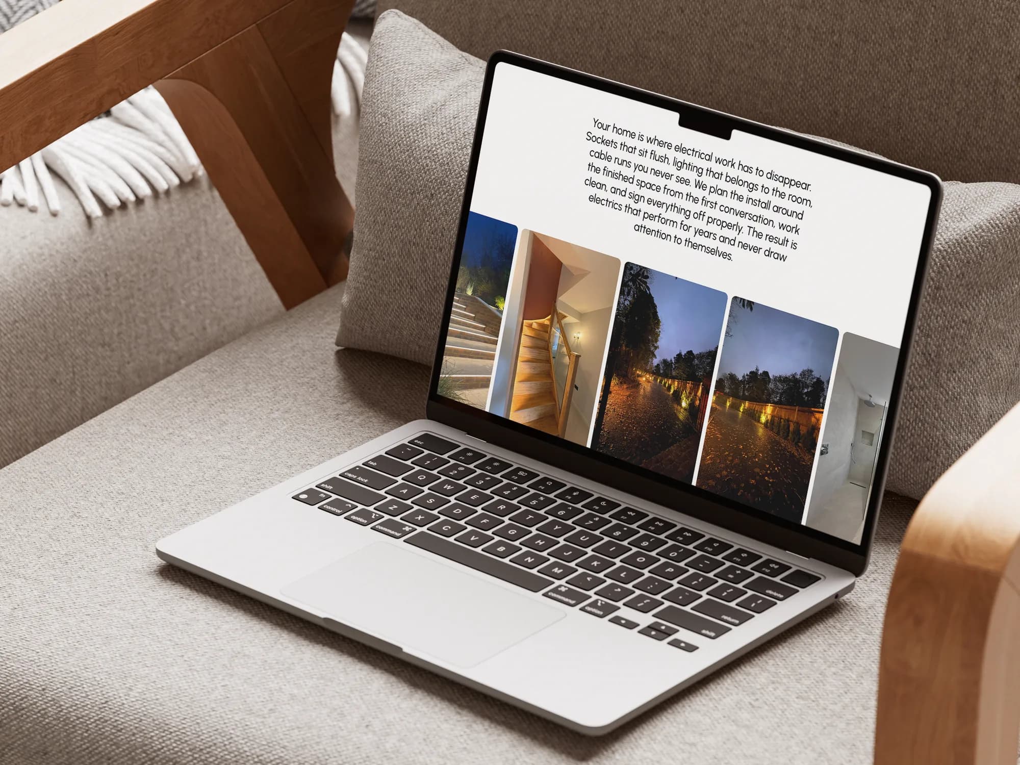 The JustElectrix residential page on a MacBook Air, on a linen armchair