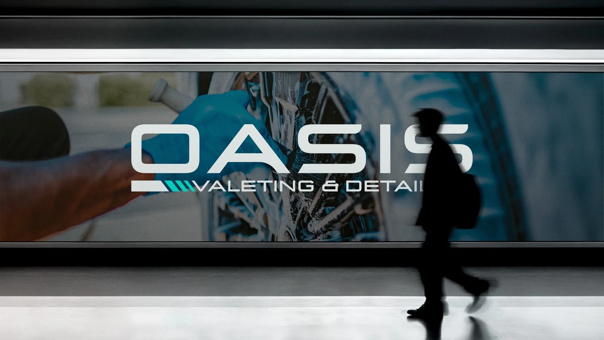 A large Oasis Valeting & Detailing billboard over a photo of a wheel being cleaned, with someone walking past