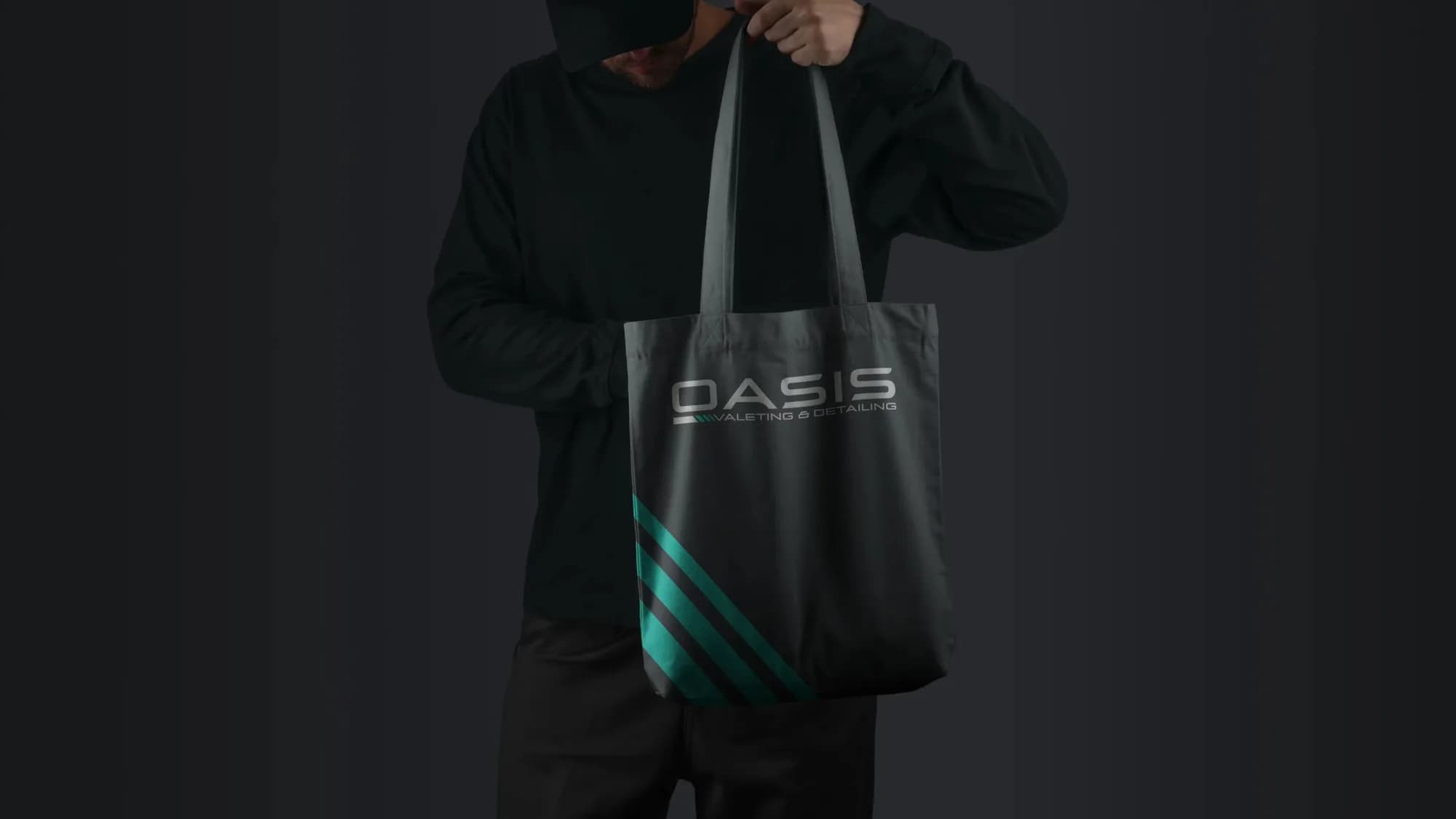 A grey Oasis tote bag with the logo and teal diagonal stripes