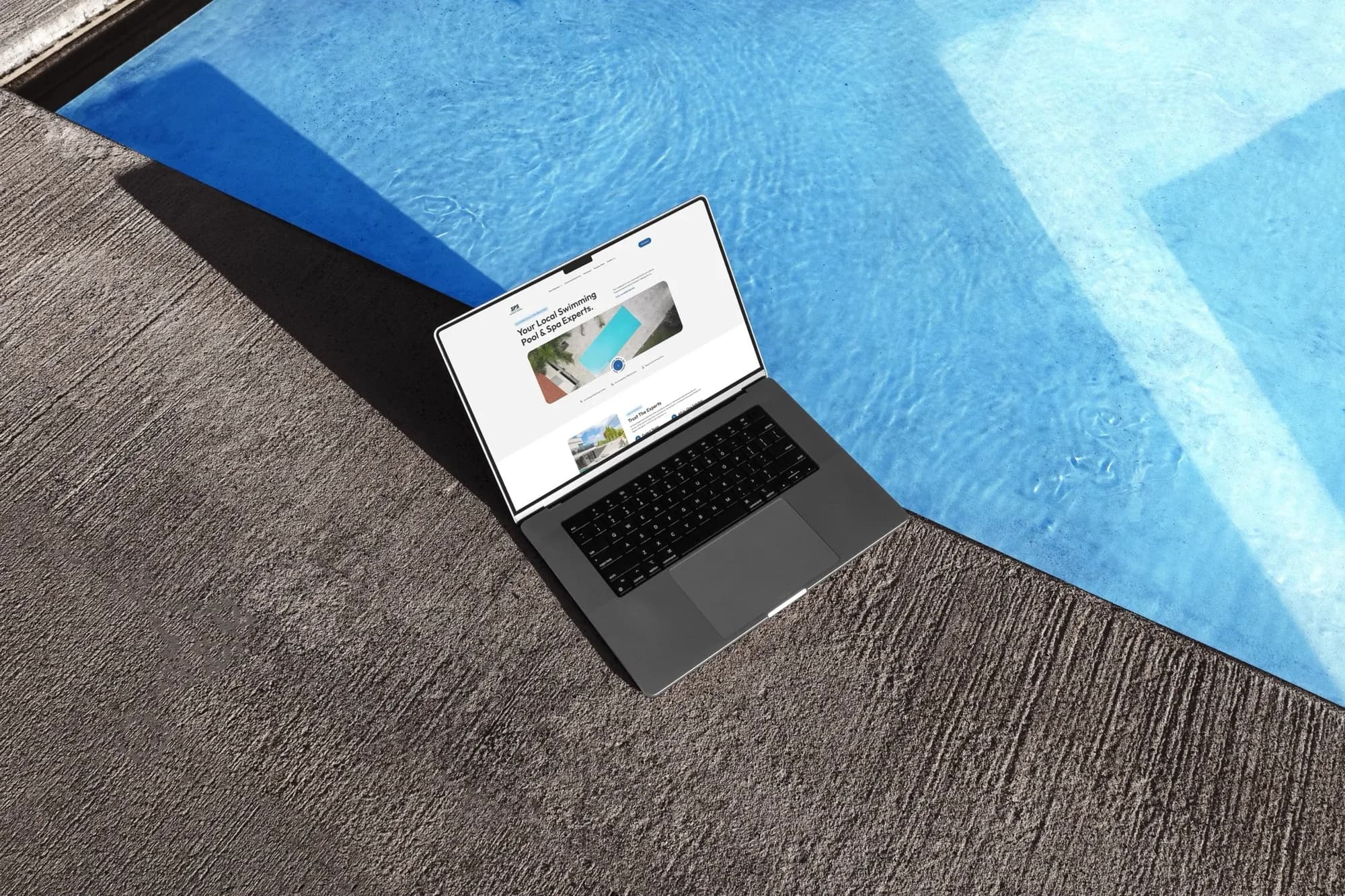 A laptop on the edge of a swimming pool showing the SPS website